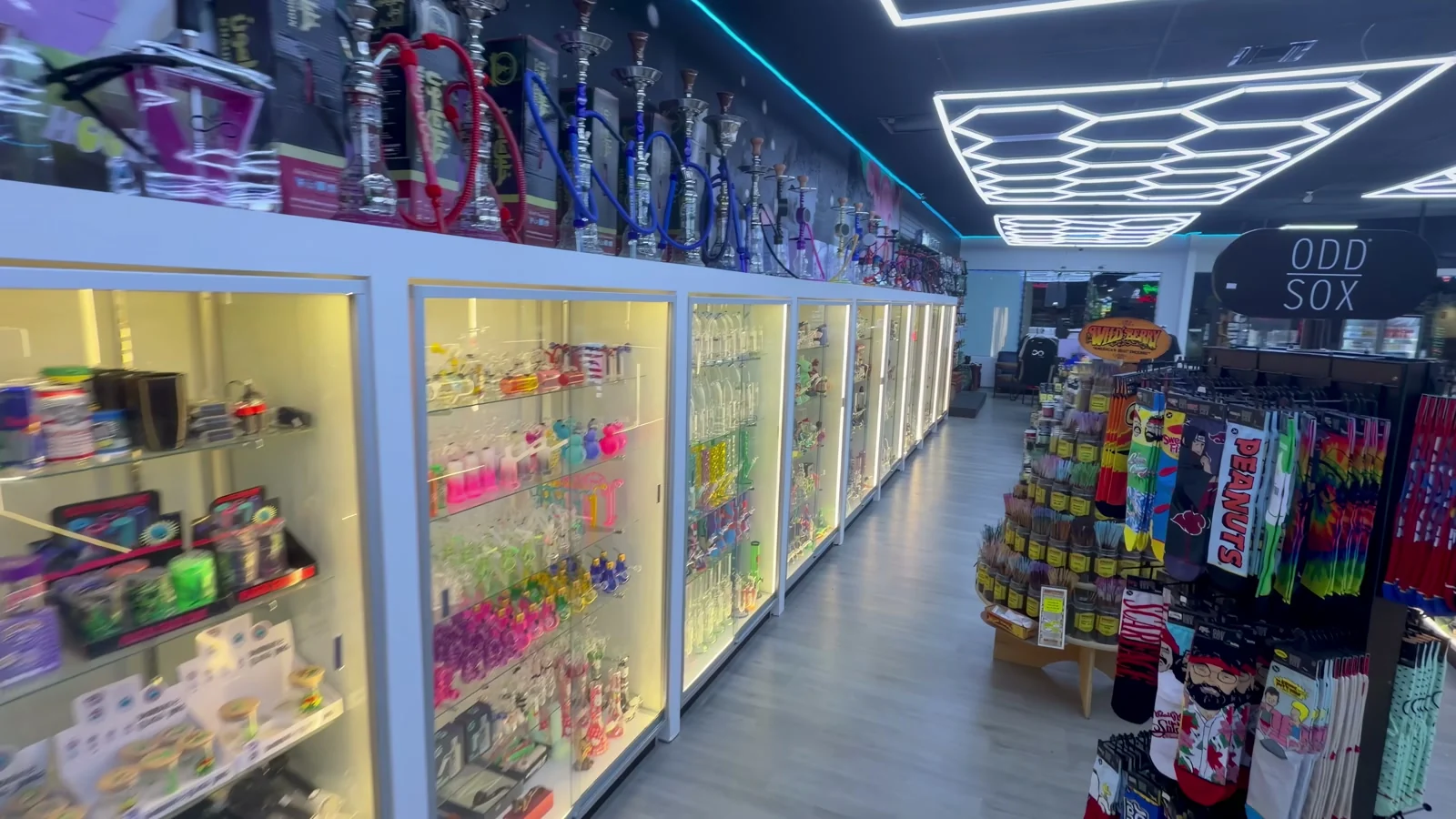 An aisle of lit glass cases with coloured glass inside and hookahs along the top