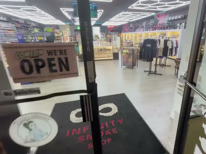 View through the open front door with a Come In We're Open sign and an infinity logo doormat