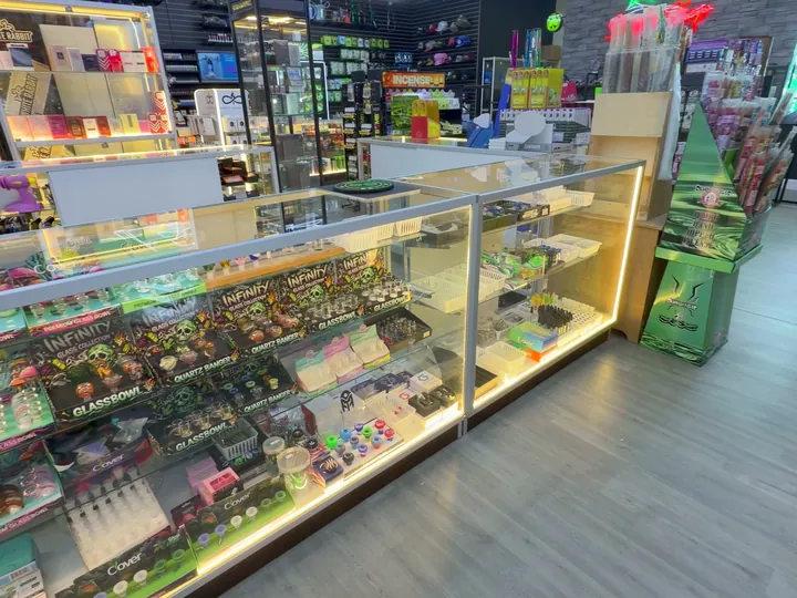 Glass counter of boxed glass accessories, with incense displays and a wall of hats behind