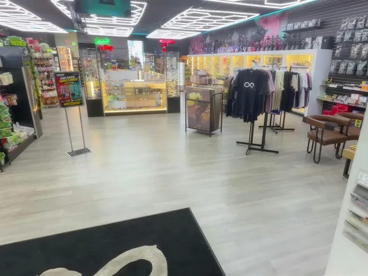 Sales floor seen from the entrance, with a lit glass case, T-shirt racks and hexagon ceiling lights